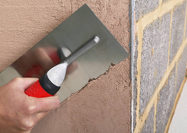 A contractor applying a skim coat for a smooth, even finish on a drywall surface.